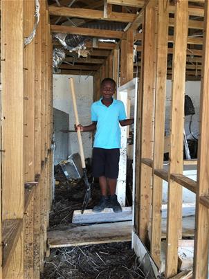 AJ Smith finds a shovel amid the rubble of his family’s home where they spent 36 hours in the attic and on the roof.