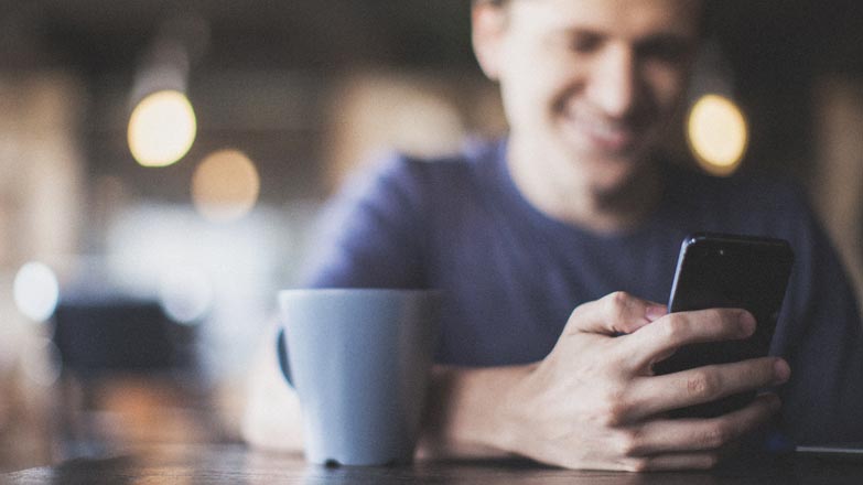 Man enjoying coffee reading stories on phone